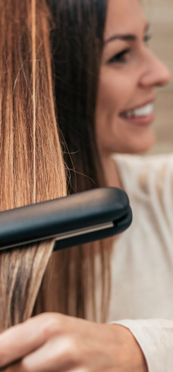 immagine di una ragazza con capelli lisci che si sta piastrando i capelli