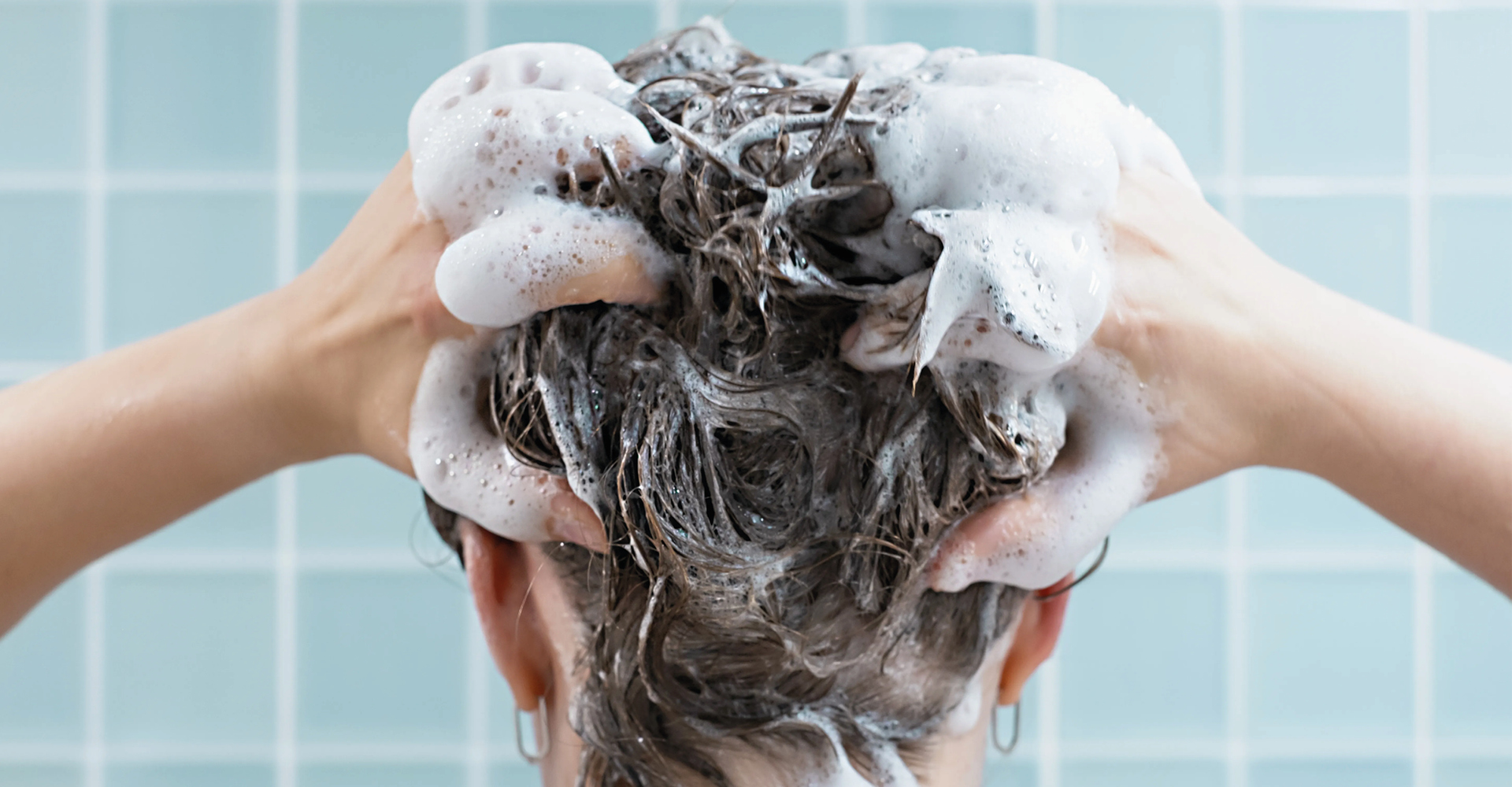 immagine di una ragazza in doccia, vista da dietro, con tutti i capelli inschiumati