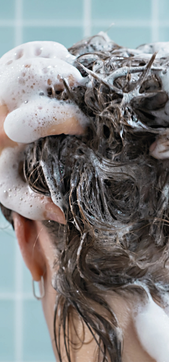 immagine di una ragazza in doccia, vista da dietro, con tutti i capelli inschiumati