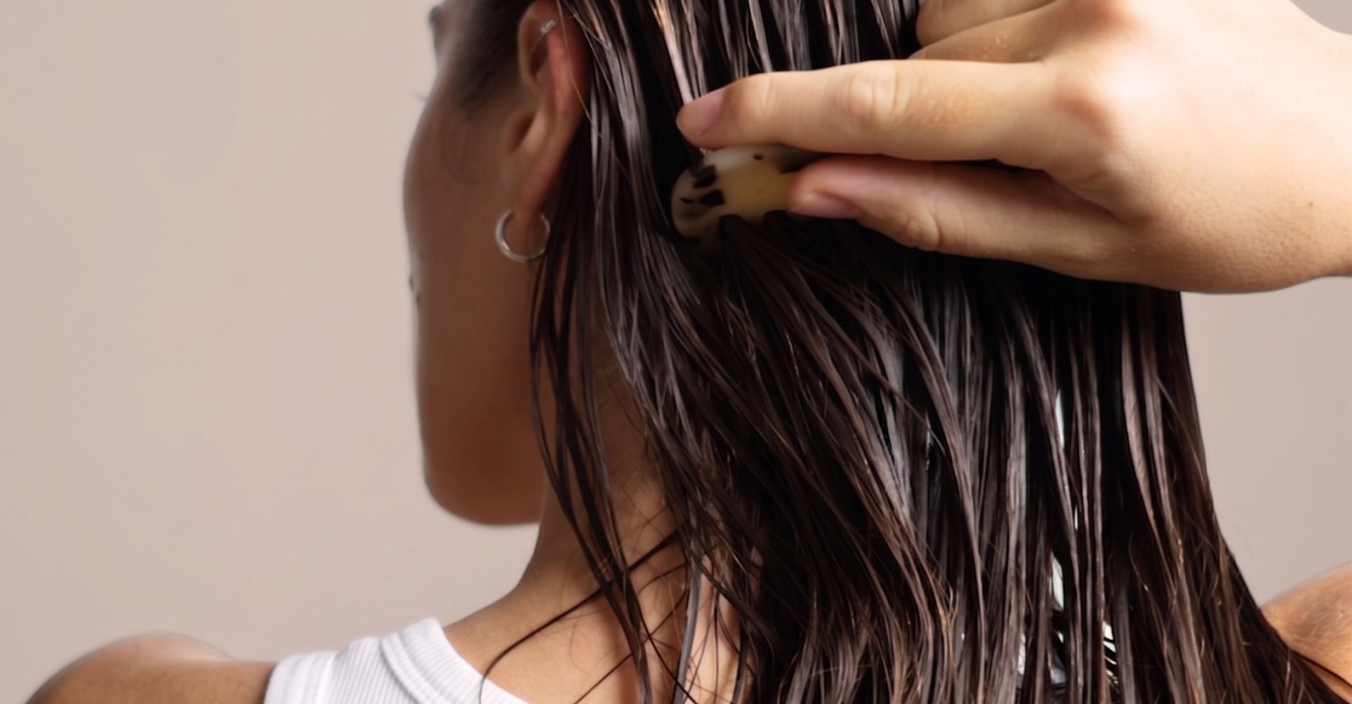immagine di una ragazza vista di spalle con capelli bagnati e una mano che si tocca i capelli