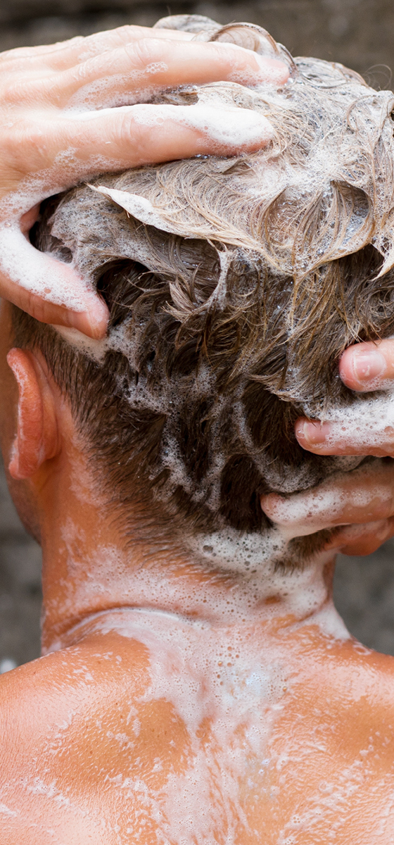 immagine di un uomo in doccia, con focus sui capelli tutti insaponati dallo shampoo